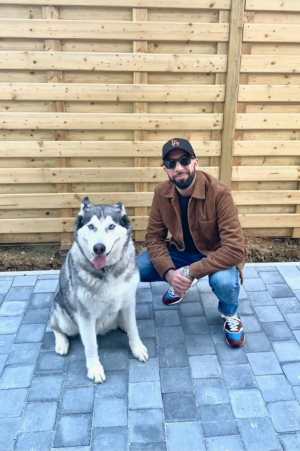 Sidarth crouched next to Alia, his husky, on a patio