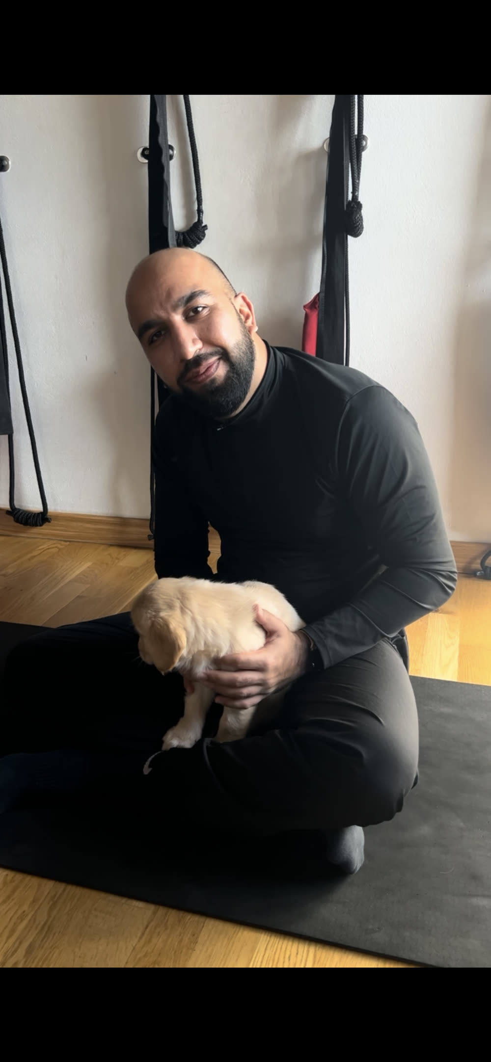 Sidarth holding a golden retriever puppy during puppy yoga